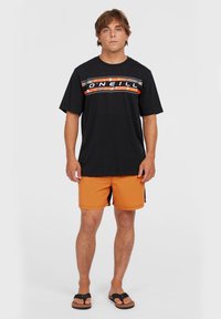 Sort kortærmet t-shirt med orange og hvid O'Neill-logo, parret med orange badebukser. Modellen bærer sorte flip-flops.