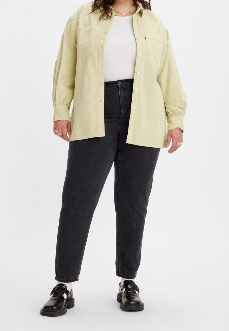 Světlězelená manšestrová košile s předními knoflíky, dvěma kapsami na prsou, doplněná černými džíny s vysokým pasem a černými botami. Viditelná plošná textura.