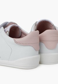 Baskets en cuir blanc avec des accents en cuir rose, dotées d'une semelle en caoutchouc blanc texturé et d'une doublure intérieure lisse. Design arrondi et bas profil.