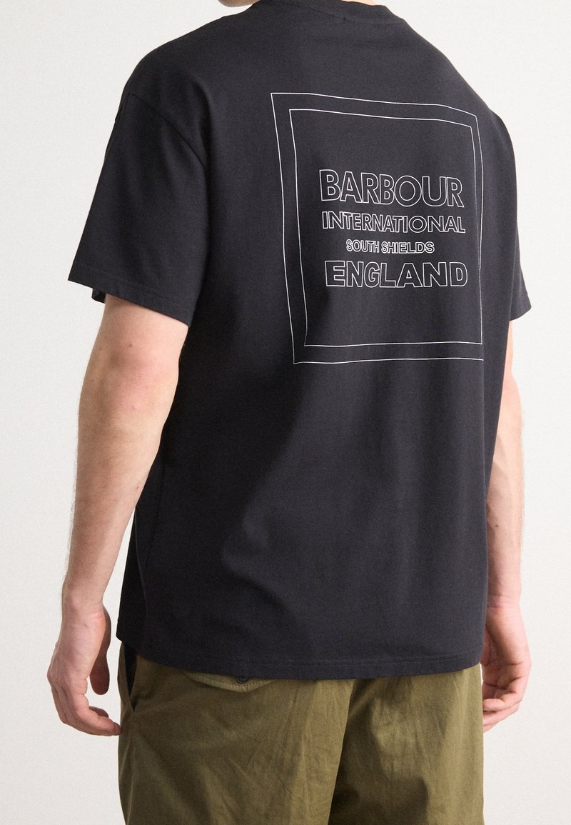 Černé bavlněné tričko s obdélníkovou bílou grafikou na zádech, na které je tučným písmem napsáno "Barbour International South Shields England".