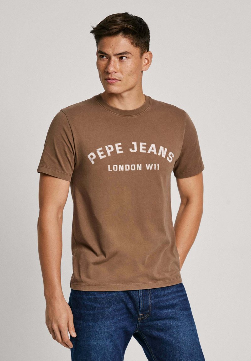 Ruda medvilnė marškinėliai trumpomis rankovėmis, su baltais užrašu "PEPE JEANS LONDON W11" ant krūtinės. Klasikinio apvalaus kaklo dizainas.