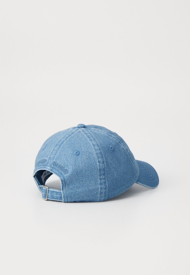Denim baseballpet in lichtblauw, met een gebogen klep, een achteraanpasbare strap en subtiele logo-omschrijvingen op de achterkant.