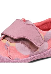 Zapato rosa tipo slip-on con suela texturizada; cuenta con una parte superior de tela suave con un patrón de burbujas y una correa ancha de Velcro para el cierre.