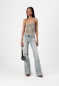 Top sin mangas gris con estampado floral y bordes ondulados, combinado con jeans acampanados de color azul claro y un bolso negro. Texturas suaves con un ajuste casual.