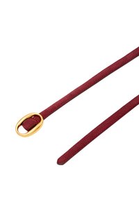Burgundská semišová pásek s hladkým povrchem, vybavený oválnou sponou ve zlatém odstínu a dvěma štíhlými popruhy vycházejícími ze spony.