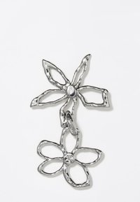 Colgante de flores de metal plateado con dos formas florales en niveles, pétalos texturizados y un acento central de piedra sostenido por una cadena.