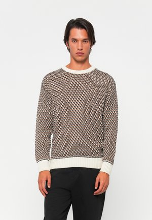 Stickad tröja i brunt, creme och svart med geometriskt mönster. Har rund halsringning och ribbade ärmslut samt nederkant. Strukturerad yta.