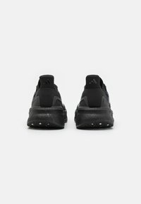 Chaussures de sport noires avec un dessus texturé, une semelle rembourrée et un panneau de talon renforcé. Design minimaliste avec un branding subtil.