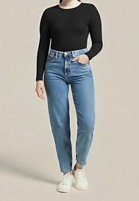 Czarny body z długim rękawem w połączeniu z niebieskimi dżinsami z wysokim stanem. Jeansy mają luźny krój i delikatne przetarcia na dole, noszone z białymi trampkami.