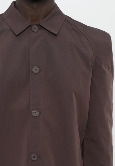 Brauner Button-Down-Mantel mit Kragen, vier Knöpfen auf der Vorderseite und einem glatten, leicht glänzenden Stoff mit Raglanärmeln.