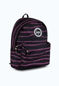 Musta reppu, jossa on vaaleanpunaiset kimallusraidat, etutasku ja pyöreä valkoinen logo-tagi. Varustettu yläkahvalla ja säädettävillä olkahihnoilla.