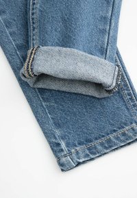 Jasnoniebieskie dżinsy z podwiniętym dołem. Posiadają klasyczny prosty krój, widoczne przeszycia oraz lekko chropowatą fakturę typową dla materiału dżinsowego.