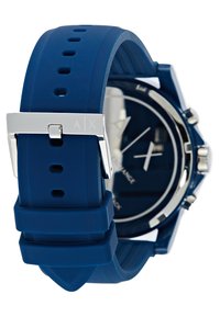 Blå silikonarmbandsur med silverdetaljer, rund urtavla, mörkblå urtavla och vita markeringar. Har ett strukturerat armband med justerbara hål.