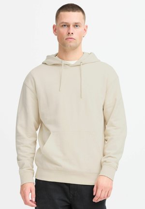Hoodie beige avec une poche frontale, capuche avec cordon de serrage et poignets côtelés. Fabriqué à partir d'un matériau doux au toucher lisse.