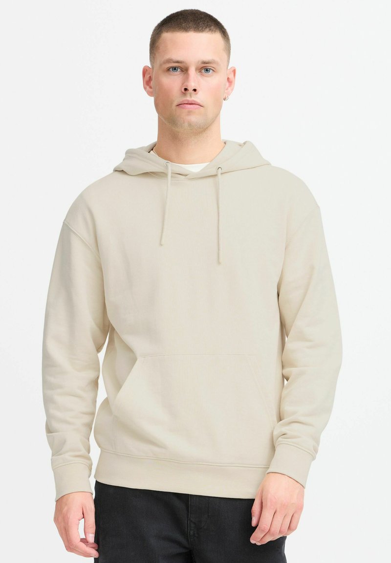 Felpa beige con tasca a marsupio frontale, cappuccio regolabile con lacci e polsini a coste. Realizzata in materiale morbido con una texture liscia.