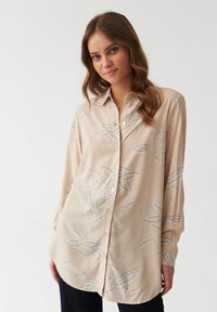 Beige Hemd aus leichtem Stoff mit floralem Muster in Grautönen, spitzem Kragen und langen Ärmeln.