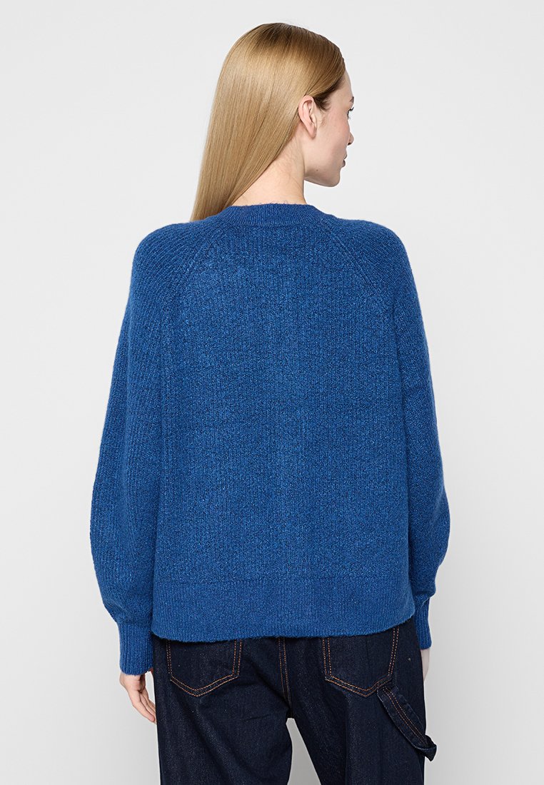 Blauer Strickpullover mit strukturiertem Finish, Raglanärmel und geripptem Saum. Die Rückseite hat ein glattes Design mit minimalen Details.