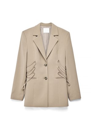 Beige tailored blazer with notch lapels, two front buttons, side lace-up detailing, and long sleeves, laid flat on a white background.