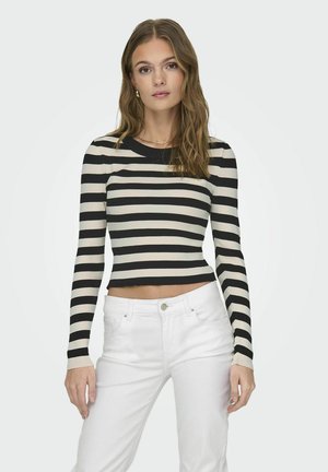 Schwarz- und cremegestreiftes, geripptes Langarmoberteil mit einem cropped Schnitt, kombiniert mit weißen Hosen. Glatte Textur, runder Ausschnitt und taillierter Schnitt.