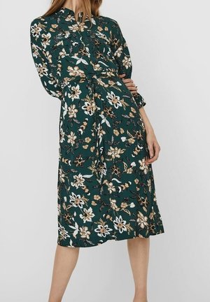 Dunkelgrünes Damen-Midi-Kleid mit beigem und weißem Blumenmuster, langen Ärmeln, vorne mit Knöpfen und Bindegürtel in der Taille.