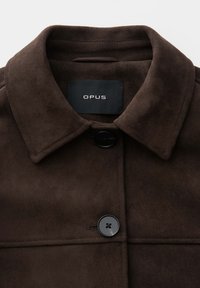 Dark brown suede jacket with pointed collar, two black buttons, and black label with "OPUS" text inside the collar.
