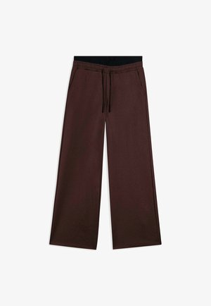 Pantalones de pierna ancha marrones con cintura elástica, cordón ajustable y bolsillos laterales. Hechos de un material suave y flexible.