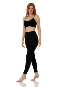 Soutien-gorge de sport noir sans couture et leggings taille haute en tissu lisse et extensible. Le soutien-gorge est doté de fines bretelles ; les leggings offrent une couverture totale.