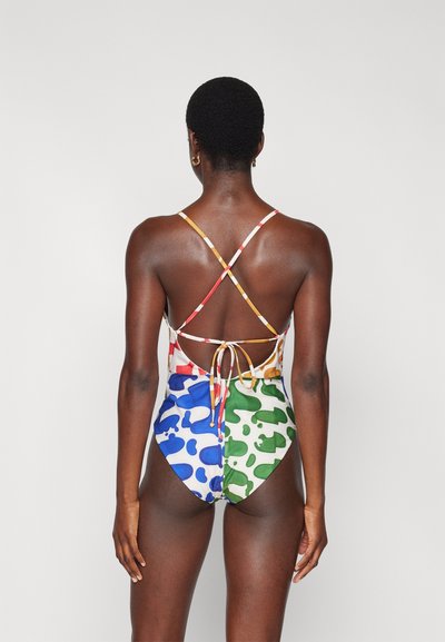 Costum de baie dintr-o singură piesă, multicolor, cu modele abstracte în nuanțe de roșu, albastru, verde și alb. Bretele încrucișate pe spate și detaliu cu funda la spate.