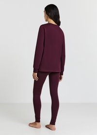 Ensemble de vêtements d'intérieur bordeaux comprenant un haut à manches longues avec un col rond et des leggings assortis ajustés avec des détails texturés sur les jambes.