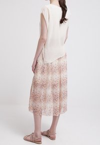 Lentävä beige mekko, jossa oranssin ja sinisen kukkakuosi; kevyt kangas; lyhyet hihat ja pidempi takahelma.