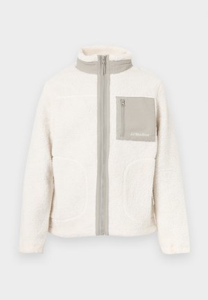 White fleece jacket with a high collar, front zipper, two side pockets, and a single chest pocket in a beige fabric. "JJ Studios" logo on pocket.