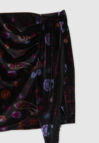 Wrap in velluto nero con motivi floreali e paisley colorati; presenta dettagli in frange lungo un lato e un design drappeggiato.