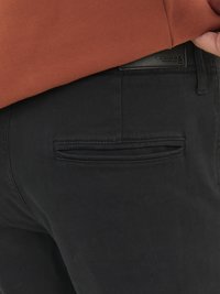 Schwarze Hosen aus weichem Stoff, die ein elegantes Design mit einem Gesäßtaschendetail und einem sichtbaren Markenetikett am Bund zeigen.