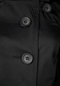 Czarna sekcja płaszcza przeciwdeszczowego z dużymi, okrągłymi guzikami na cztery dziurki, gładką teksturą i widocznymi detalami szwów.