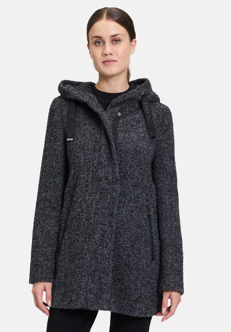 Czarny i szary wzorzysty wełniany płaszcz z kapturem, zapięcie na napy z przodu, zapinane na zamek kieszenie po bokach i regulowane paski. Gładkie, teksturowane wykończenie.