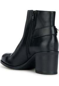 Bottine en cuir noir avec fermeture éclair latérale, bout arrondi et talon bloc texturé. Comprend un détail de bride à la cheville.