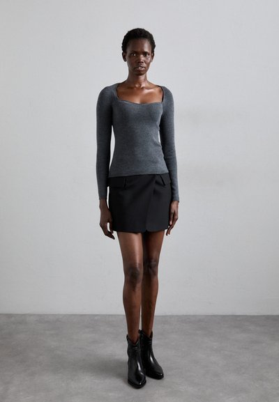 Gray ribbed long-sleeve top with a square neckline, paired with a black mini skirt featuring a scalloped hem and front pleats. Black ankle boots.