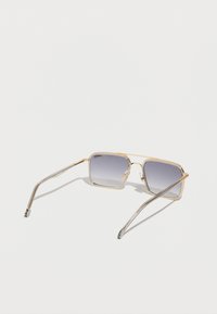 Gafas de sol cuadradas con lentes degradados, montura de metal dorado y varillas delgadas plateadas. Presentan plástico transparente cerca de las lentes y almohadillas nasales ajustables.