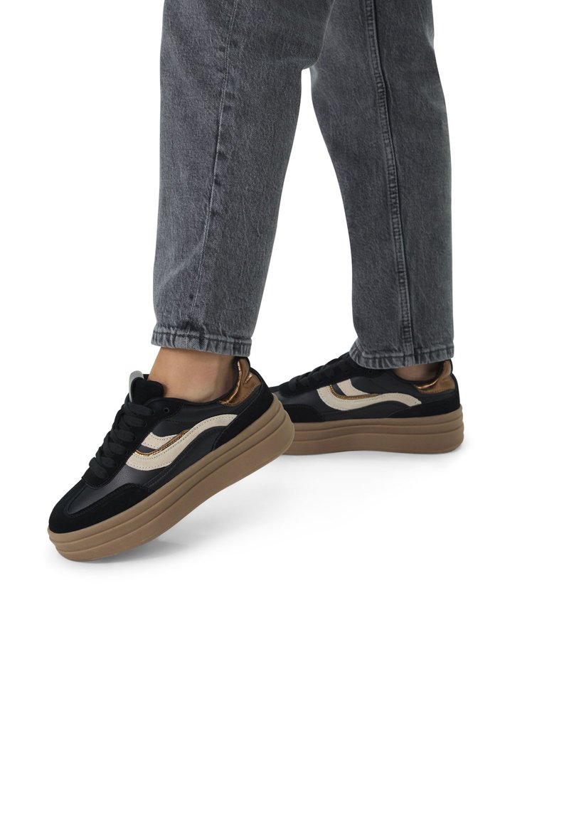 Sneakers platform neri e beige realizzati in materiali scamosciati e in pelle, con una spessa suola in gomma marrone e allacciatura anteriore.