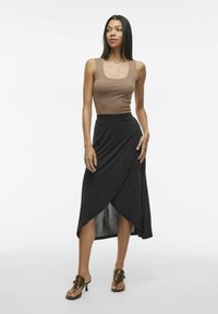 Brown tank top, black wrap skirt with side split, smooth fabric, and heeled sandals with a strap detail. Simple and modern design.
