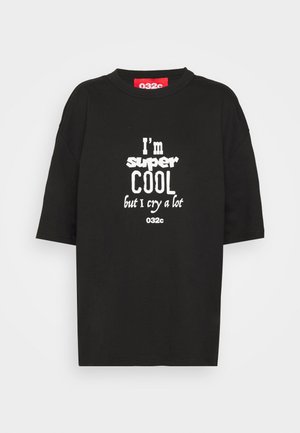 Musta lyhythihainen t-paita, jossa valkoinen teksti "I'm super COOL but I cry a lot" ja punainen etiketti kauluksen sisällä, jossa on "032c" brändi.