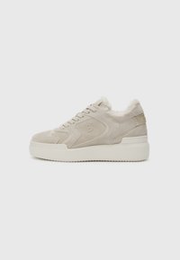 Beez suede tossud jalatsid, millel on pehme vooder, ümar varvas ja paks valge tallaosa. Omab logo detaili külgedel ja beeži aktsente.