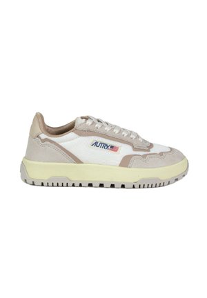 Zapatillas beige y blancas con materiales de malla y gamuza, que cuentan con una suela amarilla en contraste y un logo azul en el lateral. Detalles texturizados evidentes.
