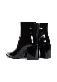 Bottines noires avec une finition brillante, bout pointu et talon carré épais. Elles possèdent une fermeture éclair à l'arrière pour plus d'accessibilité.