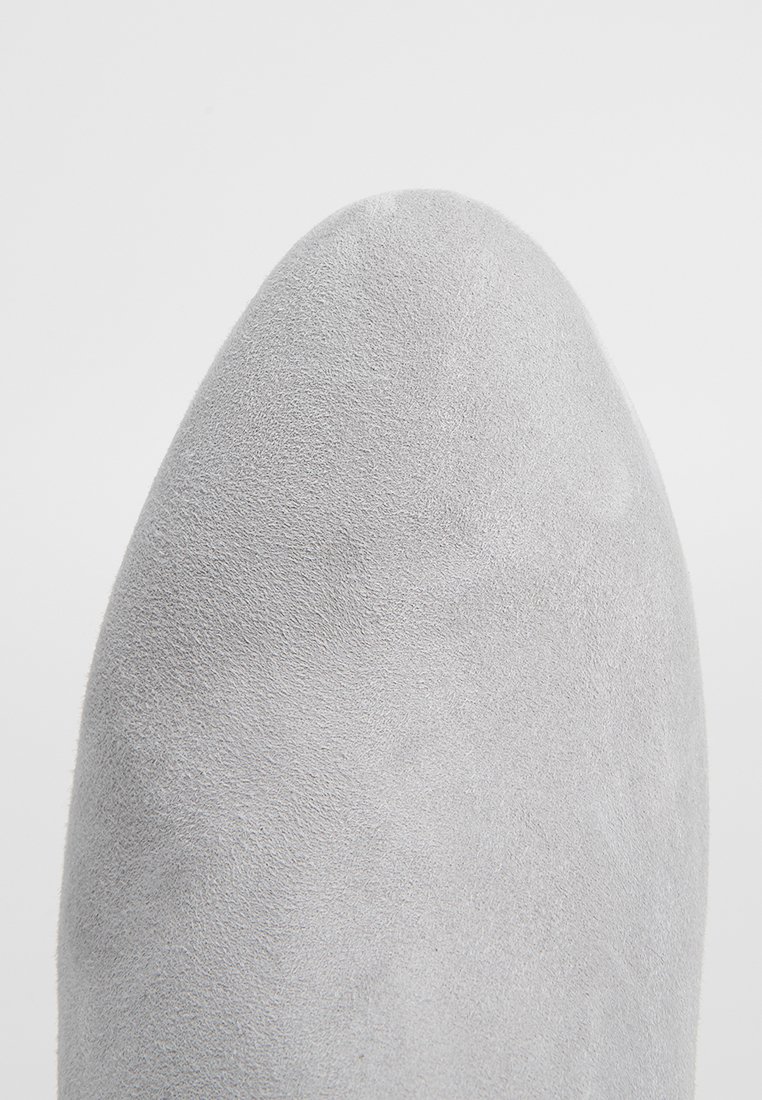 Nahaufnahme einer hellgrauen Wildlederschuhspitze mit einer glatten, runden Form und feiner, strukturierter Oberfläche.