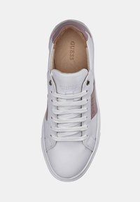 Baskets en cuir blanc avec accents roses, bout rond, lacets plats blancs et logo embossé « GUESS » sur le côté. Texture lisse et design épuré.