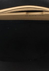 Interno di una borsa nera con texture liscia e fodera marrone chiaro. Presenta una tasca piatta e cuciture rinforzate lungo i bordi.