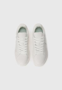 Hvide lædersneakers med en glat tekstur, matchende snørebånd og en blød mintgrøn indersål. Guldbranding på siden. Rund tå-design.