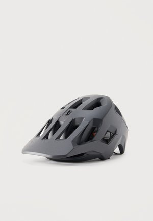 Casco de bicicleta de montaña gris mate con múltiples aberturas de ventilación y una visera extendida en la parte frontal sobre un fondo liso.