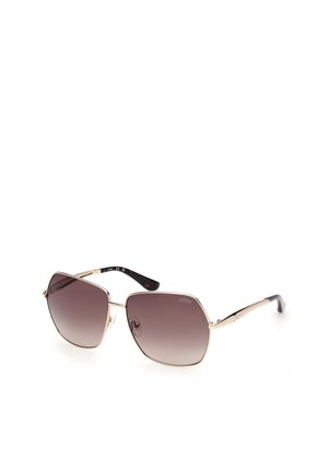 Sonnenbrille mit goldfarbenem Metallgestell, großen, eckigen braunen Verlaufsgläsern und schwarzen Bügelenden, mit dem Schriftzug "GUESS" auf dem Glas.